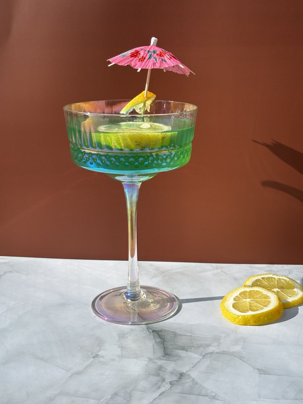 Blue and green cocktail with a paper umbrella